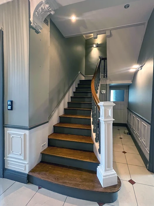 Escalier intérieur résidentiel avec marches en bois et contremarches grises, rampe blanche avec balustres noirs