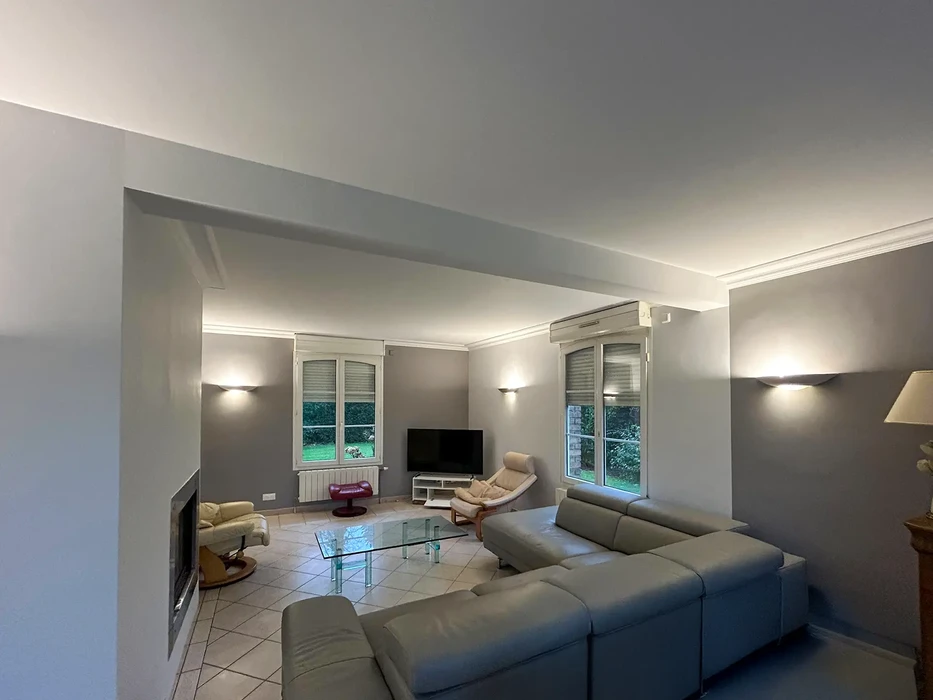 Salon moderne avec canapé gris, fauteuil beige et table basse en verre