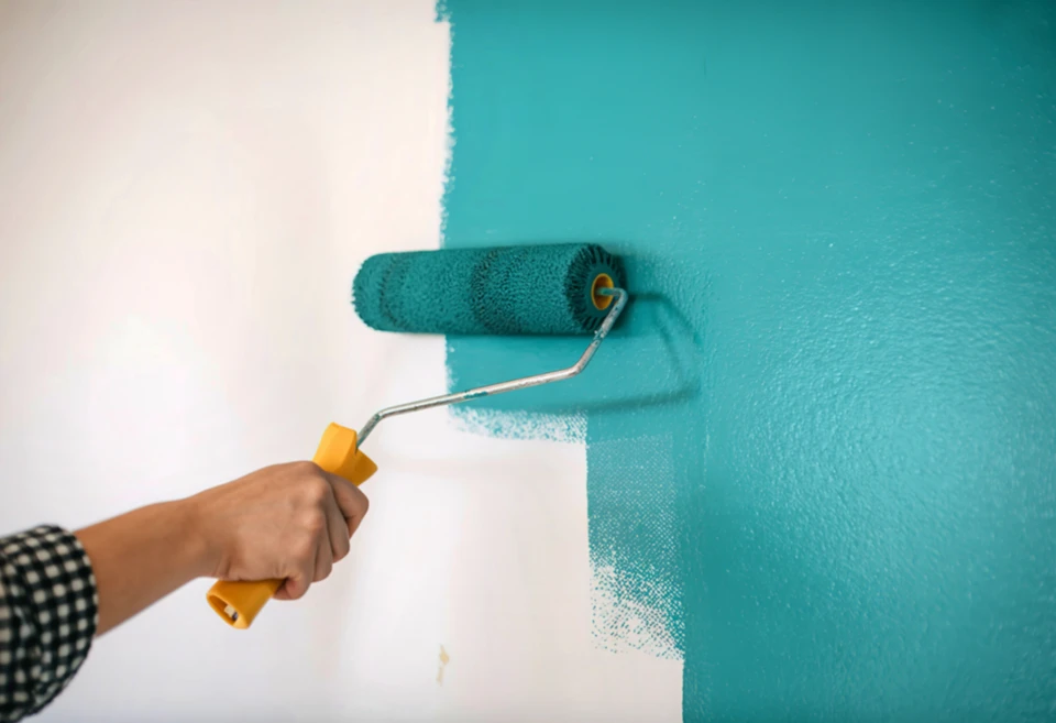 Scène d'intérieur avec pots de peinture ouverts disposés sur surface sombre, nuancier couleurs déployé en éventail, pinceau plat posé sur contenants